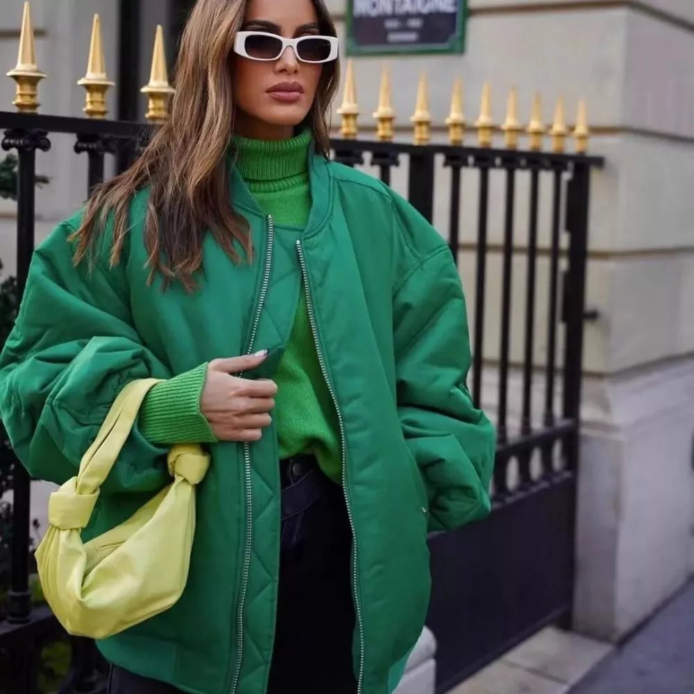 Piumino verde oversize con maniche ampie e zip centrale, donna in strada